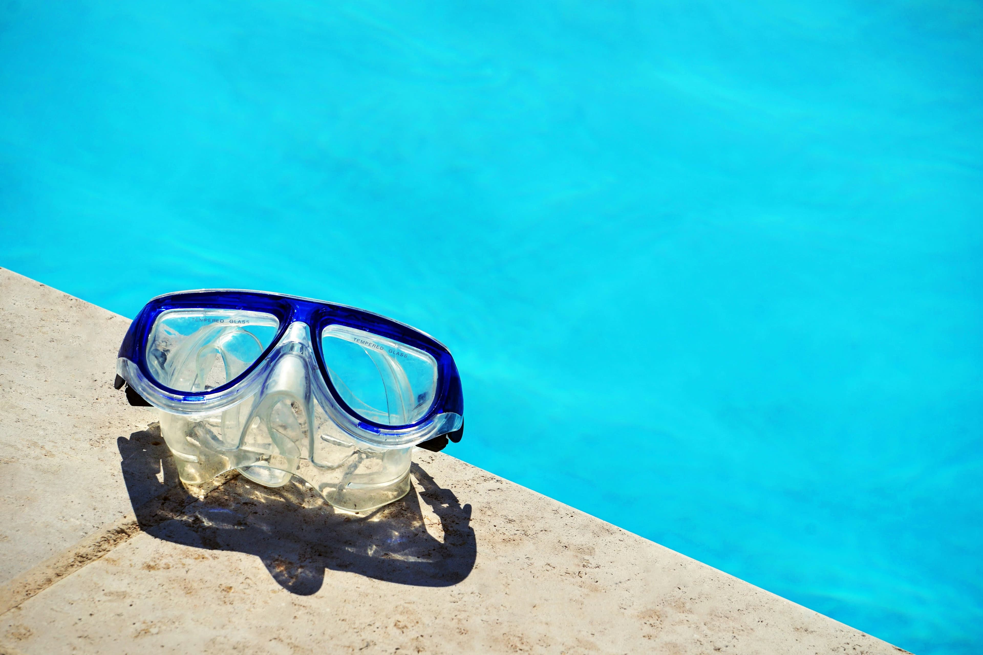 Photo of the edge of the pool with a scuba mask resting on the side.