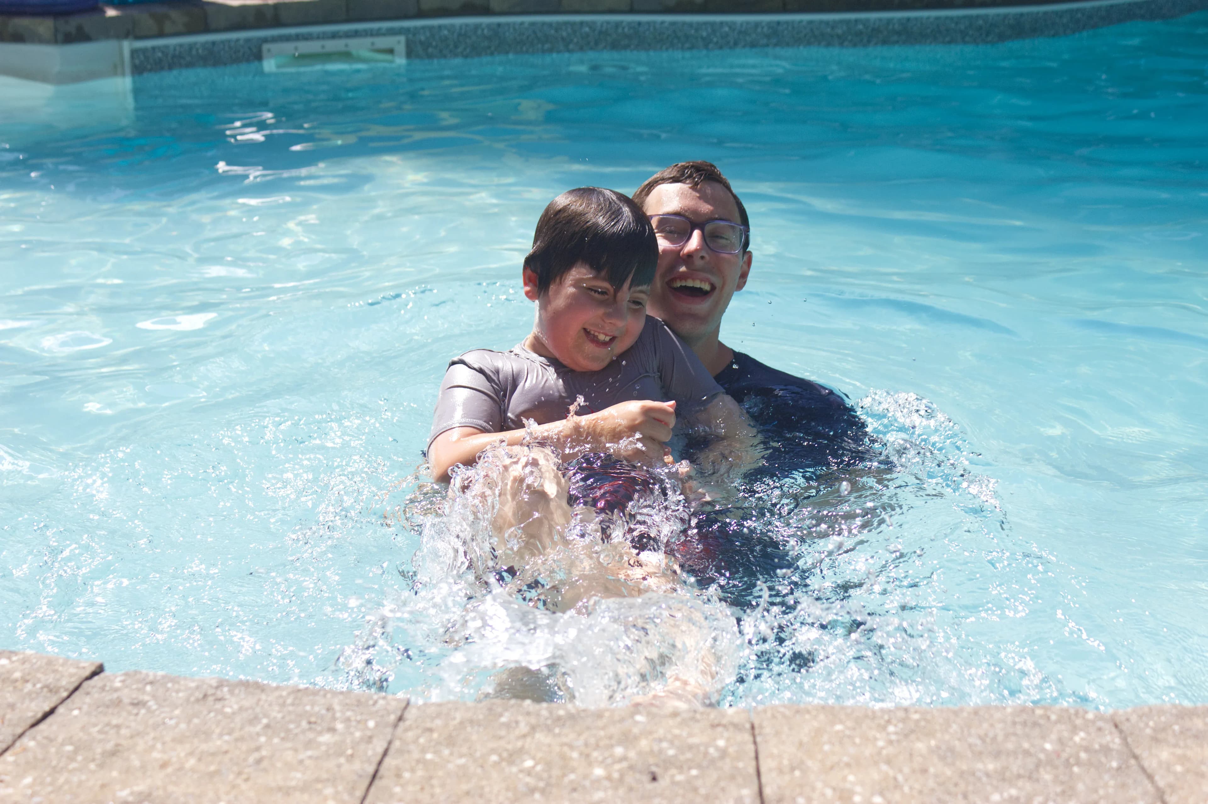 A happy swimmer splashing with his instructor.